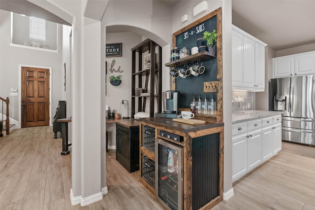 kitchen featuring light wood-type flooring, stainless steel fridge, and beverage cooler