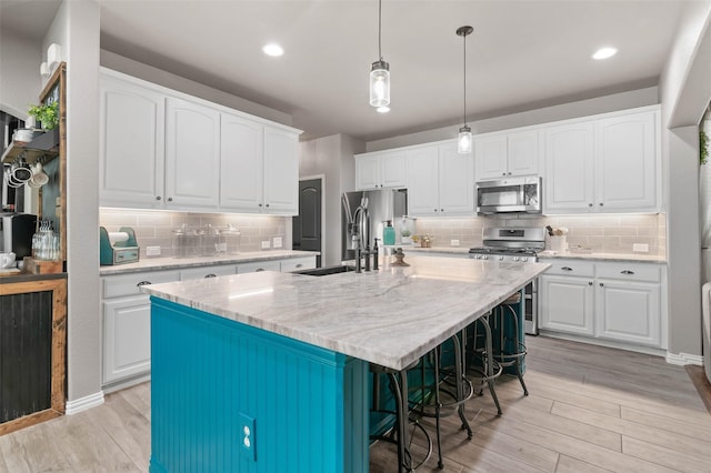 kitchen with white cabinetry, light wood-style flooring, appliances with stainless steel finishes, and a sink