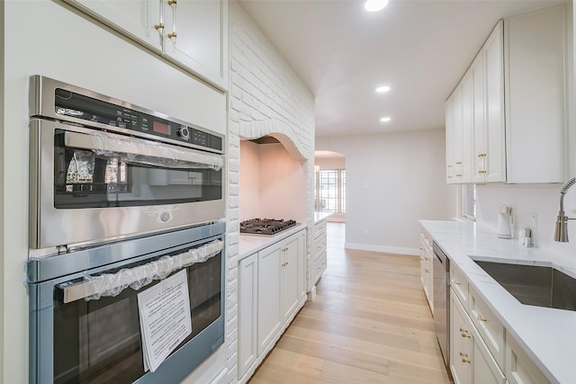 kitchen featuring recessed lighting, a sink, white cabinetry, appliances with stainless steel finishes, and light wood-type flooring