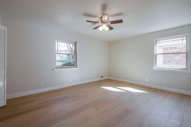 unfurnished room featuring light wood-type flooring, plenty of natural light, and baseboards