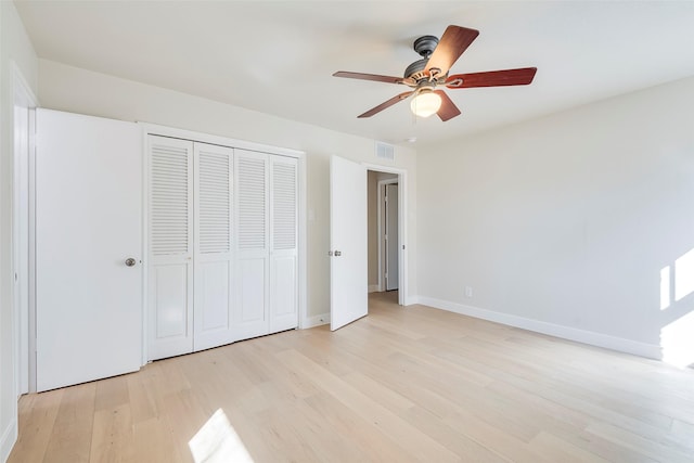 unfurnished bedroom featuring a closet, visible vents, light wood-style flooring, a ceiling fan, and baseboards