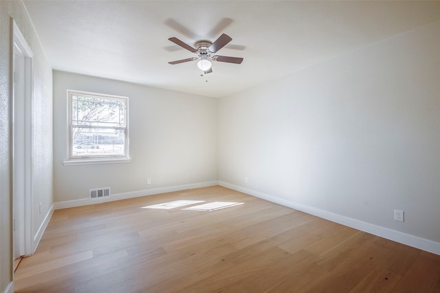 spare room featuring light wood finished floors, baseboards, visible vents, and a ceiling fan