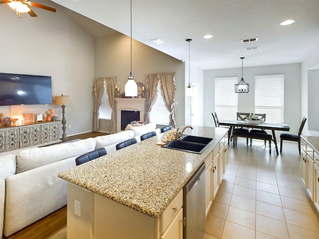 kitchen with a fireplace, a sink, visible vents, open floor plan, and stainless steel dishwasher