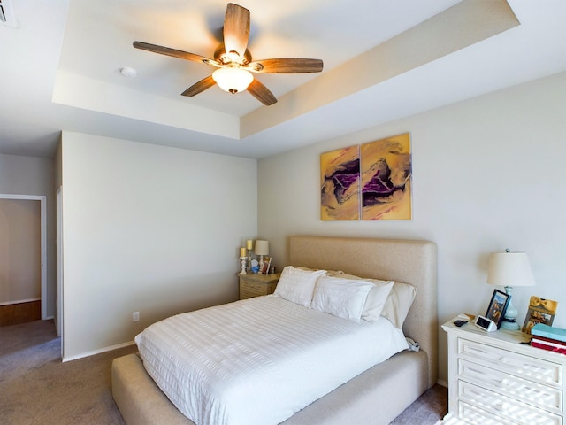 carpeted bedroom featuring visible vents, a raised ceiling, a ceiling fan, and baseboards