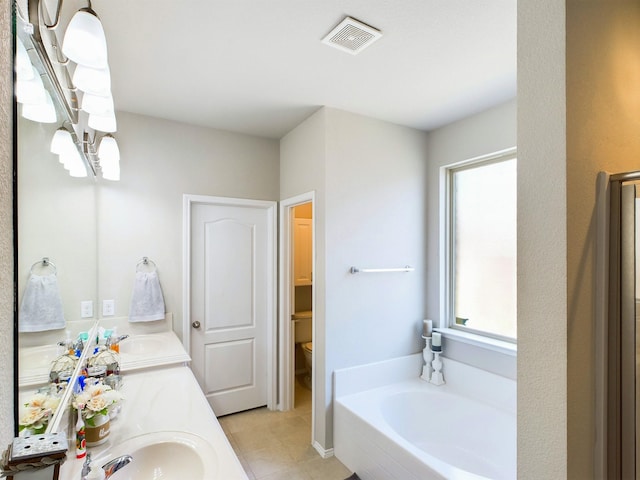 bathroom featuring toilet, a garden tub, visible vents, and vanity