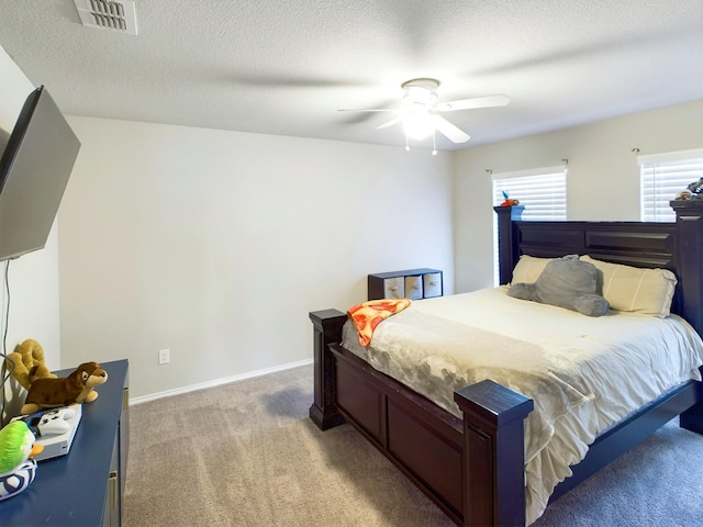 bedroom with ceiling fan, a textured ceiling, light carpet, visible vents, and baseboards