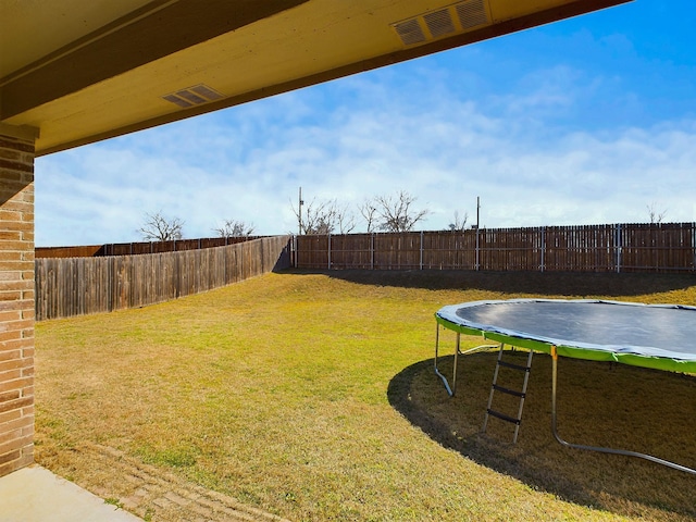 view of yard featuring a fenced backyard, a trampoline, and visible vents