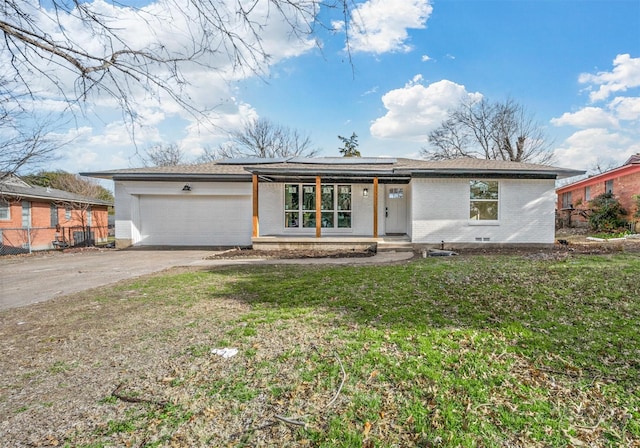 mid-century inspired home featuring a garage, solar panels, concrete driveway, a front lawn, and brick siding