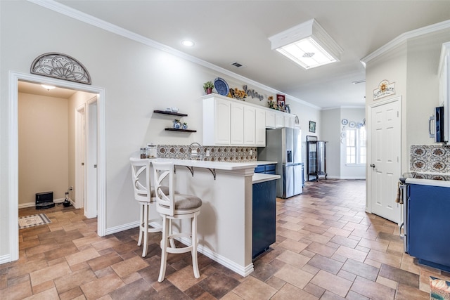 kitchen with stainless steel appliances, light countertops, decorative backsplash, white cabinetry, and a kitchen breakfast bar