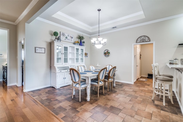 dining room featuring visible vents, crown molding, a tray ceiling, and baseboards