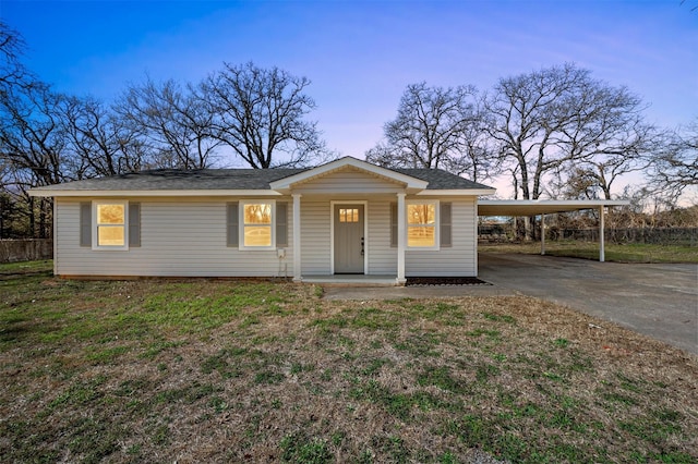 view of front of home featuring driveway, an attached carport, and a lawn