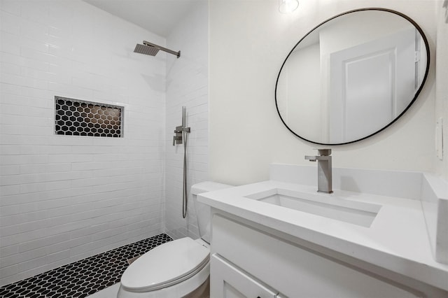 bathroom with toilet, tiled shower, and vanity