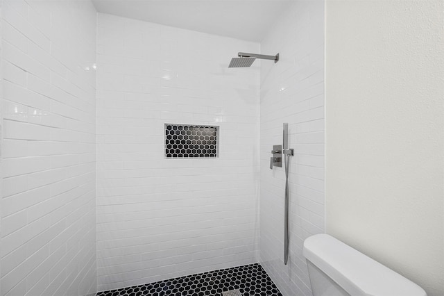 full bathroom featuring a tile shower and toilet