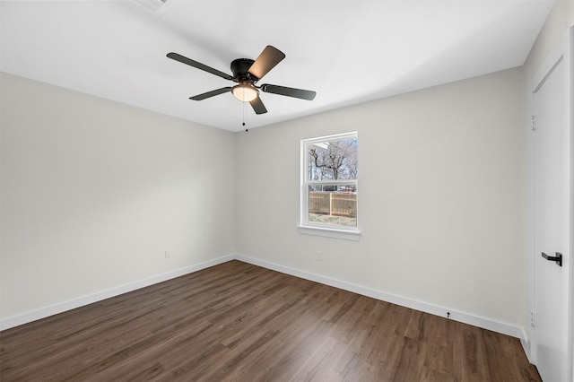 unfurnished room featuring dark wood-type flooring, a ceiling fan, and baseboards