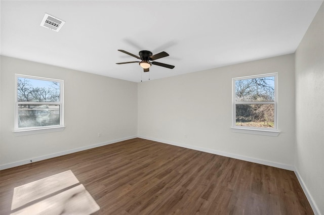 empty room featuring dark wood-type flooring, visible vents, baseboards, and a ceiling fan