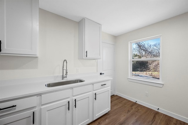 kitchen with light countertops, a sink, dark wood finished floors, and white cabinets