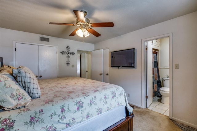 bedroom featuring visible vents, multiple closets, light colored carpet, ensuite bath, and a ceiling fan