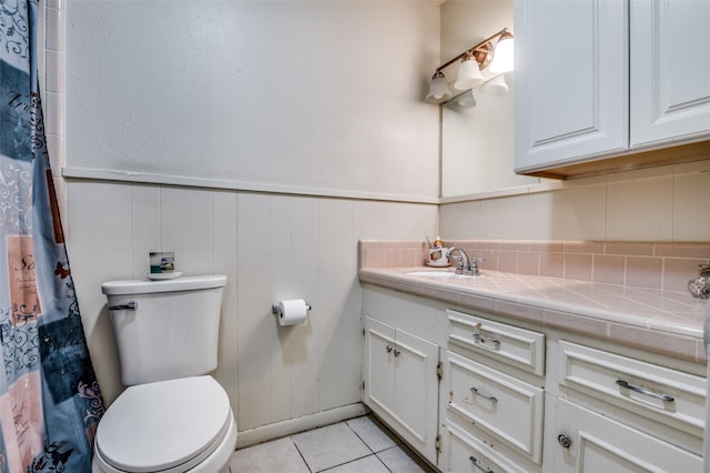 full bathroom with vanity, a wainscoted wall, tile patterned flooring, curtained shower, and toilet