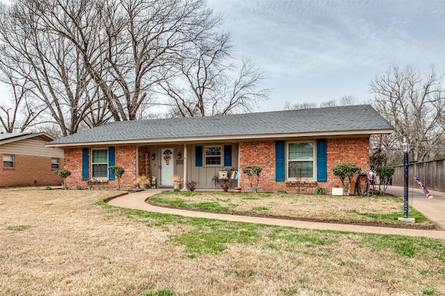 ranch-style home featuring fence, a shingled roof, a front lawn, board and batten siding, and brick siding