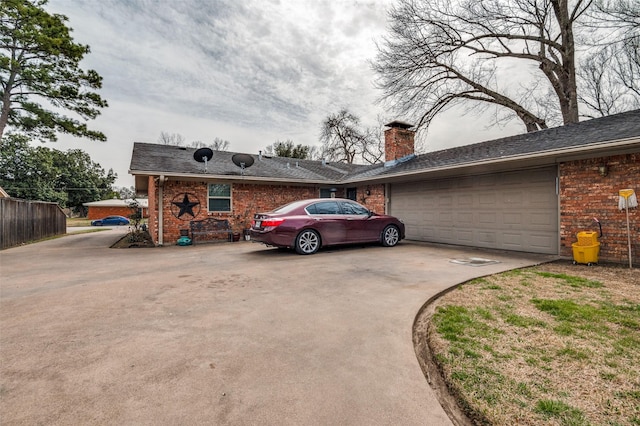 exterior space with brick siding, an attached garage, fence, a chimney, and driveway