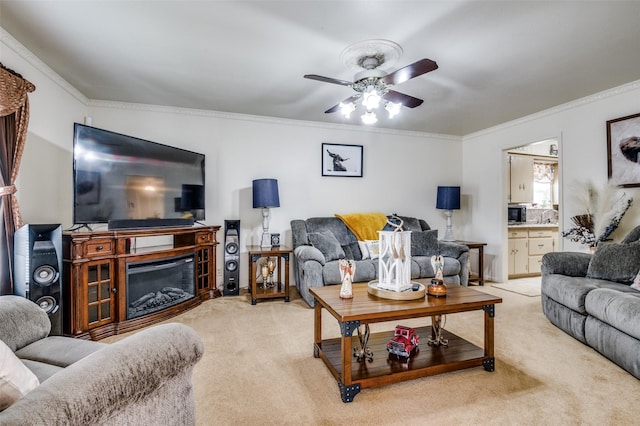 living room with ceiling fan, light carpet, a glass covered fireplace, and crown molding