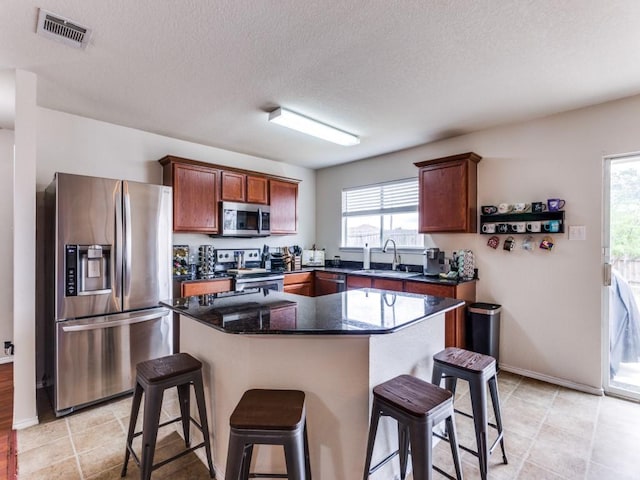 kitchen with visible vents, stainless steel appliances, a sink, and a kitchen breakfast bar