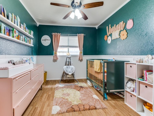 bedroom featuring crown molding, a wainscoted wall, ceiling fan, and wood finished floors
