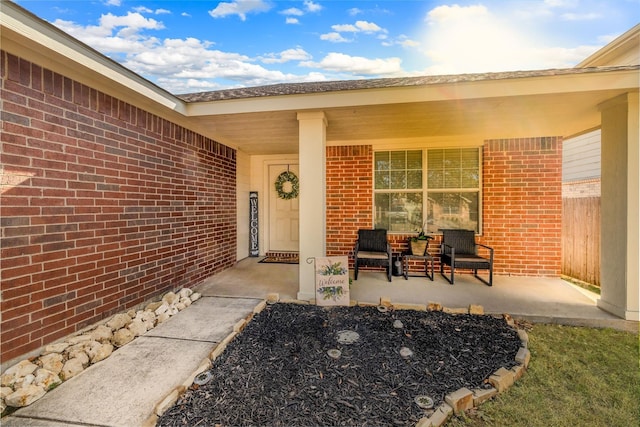 doorway to property featuring a porch and brick siding