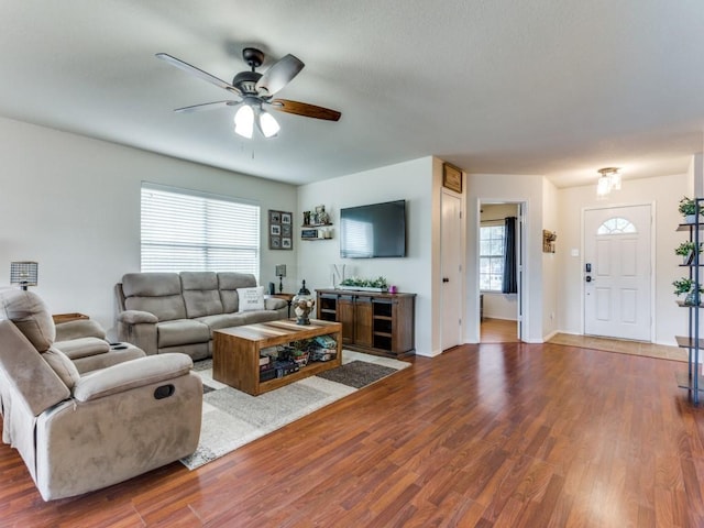 living room featuring ceiling fan, baseboards, and wood finished floors