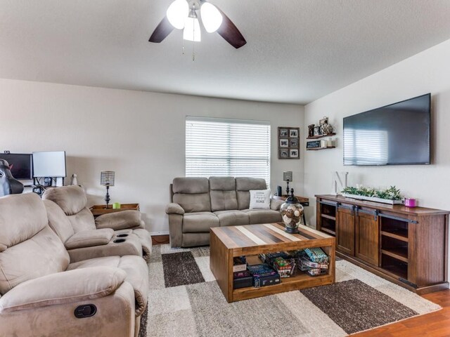 living area with light wood-type flooring, ceiling fan, and a textured ceiling