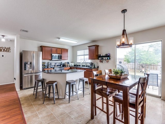 kitchen featuring stainless steel appliances, a sink, visible vents, a kitchen breakfast bar, and a center island