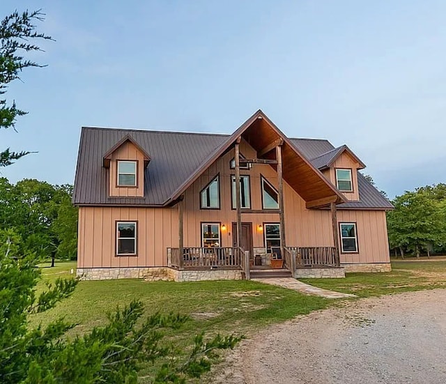 back of house featuring board and batten siding, metal roof, and a lawn