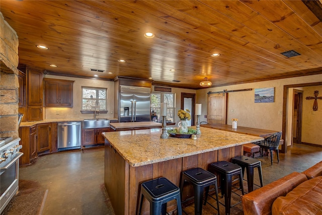 kitchen featuring a barn door, concrete floors, a sink, high quality appliances, and an island with sink