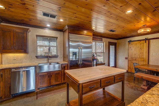 kitchen featuring visible vents, a barn door, appliances with stainless steel finishes, a sink, and concrete flooring