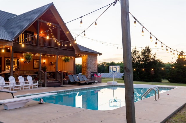 outdoor pool with a diving board and a patio