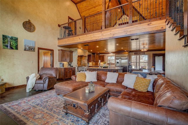 living area featuring a textured wall, a high ceiling, concrete floors, and wood ceiling