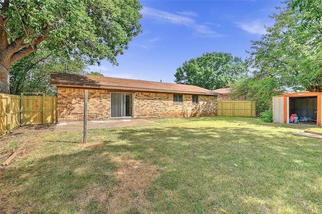 view of yard featuring a patio area, a fenced backyard, a shed, and an outbuilding