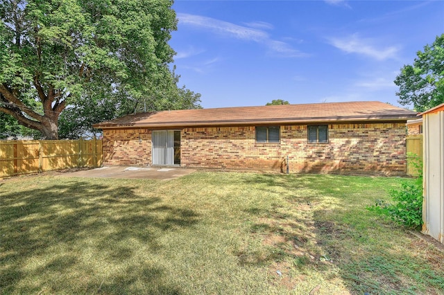 rear view of property featuring a yard, brick siding, a patio, and fence