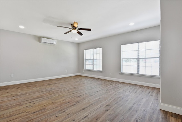 empty room featuring recessed lighting, wood finished floors, a ceiling fan, baseboards, and a wall mounted air conditioner