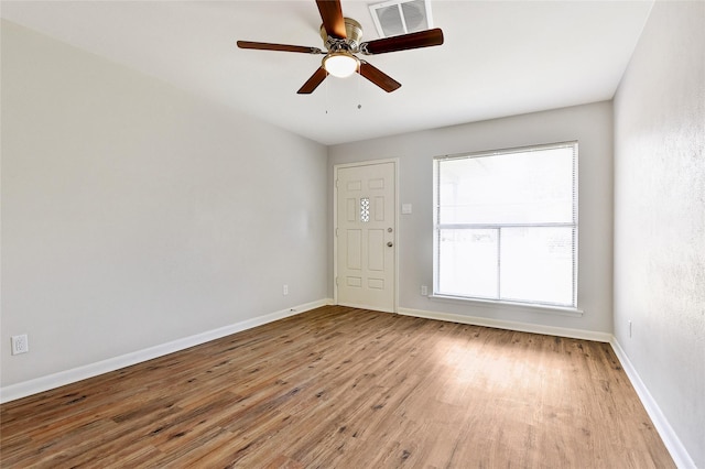 empty room with visible vents, ceiling fan, baseboards, and wood finished floors