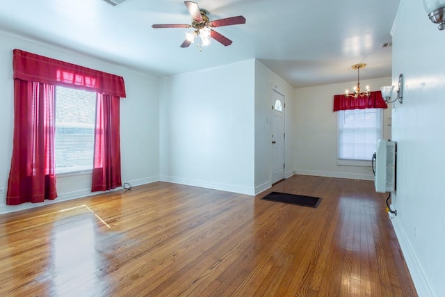 interior space with heating unit, baseboards, a wealth of natural light, and wood finished floors