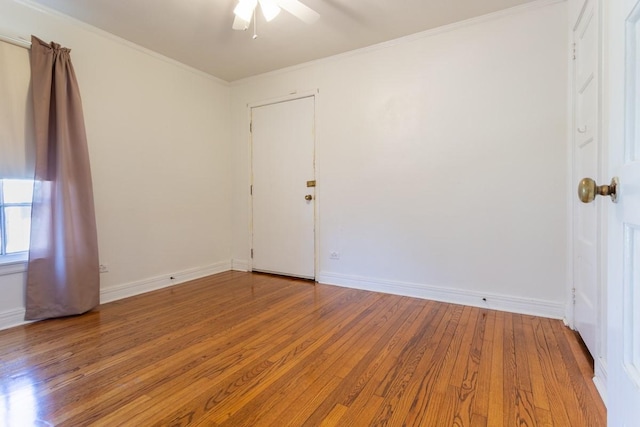 spare room featuring baseboards, hardwood / wood-style floors, and crown molding