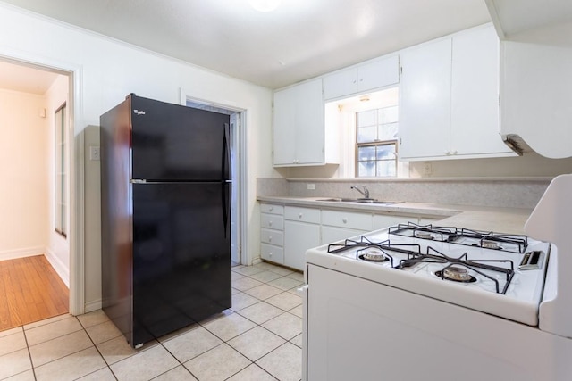 kitchen featuring light tile patterned floors, white range with gas stovetop, a sink, light countertops, and freestanding refrigerator