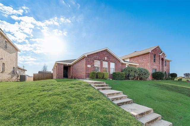 view of front of property with brick siding, fence, a front lawn, and central air condition unit