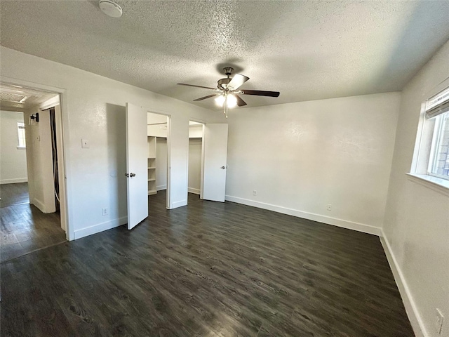 3616 Parkridge Dr Unit 108, Dallas, TX 75234 - unfurnished bedroom featuring a ceiling fan, a walk in closet, a textured ceiling, baseboards, and dark wood-style flooring