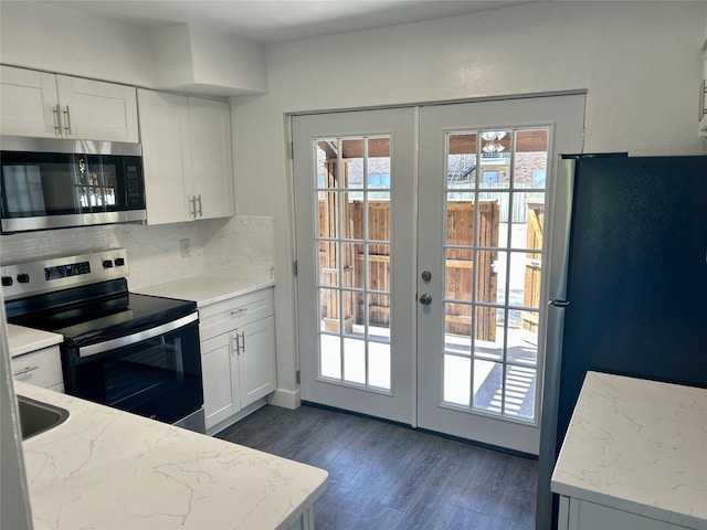 kitchen featuring dark wood-type flooring, stainless steel appliances, french doors, white cabinetry, and backsplash