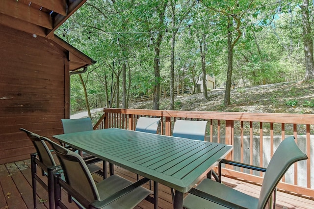 wooden deck featuring outdoor dining area and a view of trees