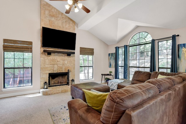 carpeted living room with high vaulted ceiling, a stone fireplace, and a ceiling fan