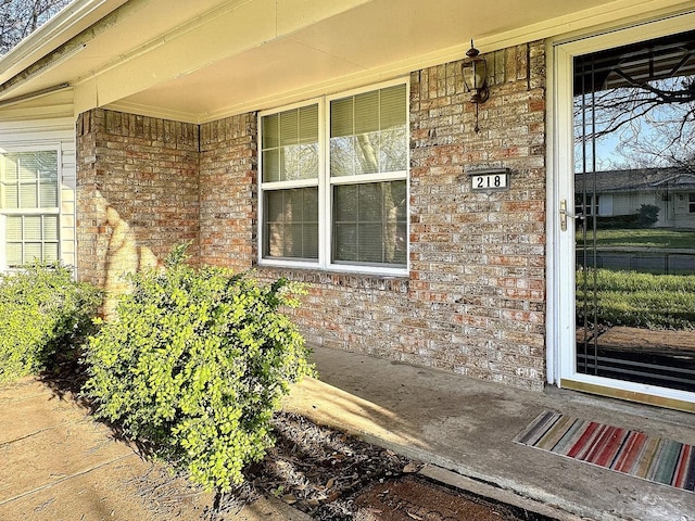 property entrance featuring a porch and brick siding