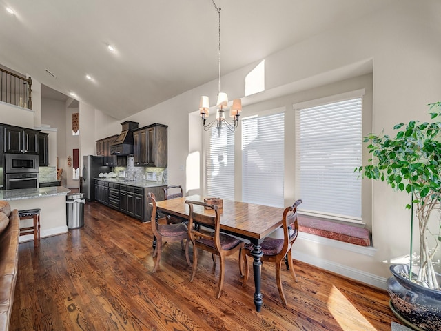 dining space featuring high vaulted ceiling, dark wood finished floors, a notable chandelier, and baseboards